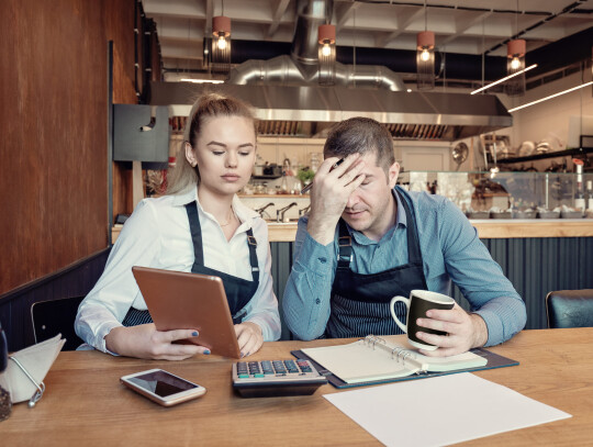 Depressed male and female entrepreneurs overwhelmed by finance problems - Nervous manager checking restaurant finance